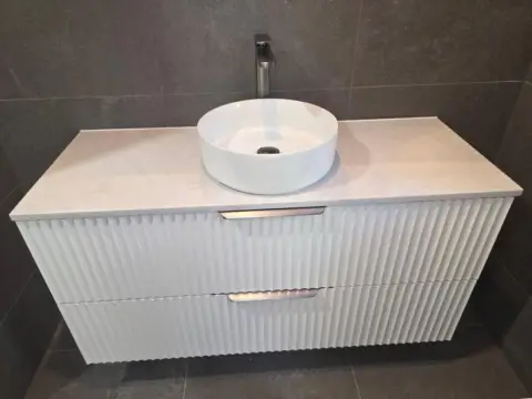 Fluted white vanity with a round vessel basin