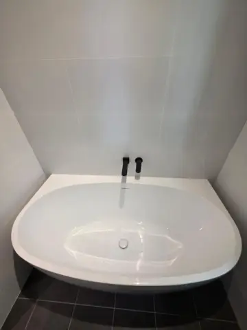 Freestanding bath with black floor-mounted mixer