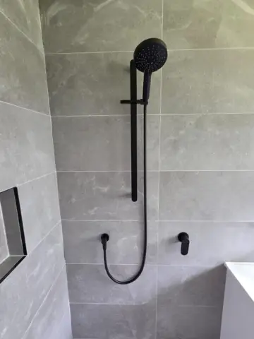 Matte black shower rail on grey tiles