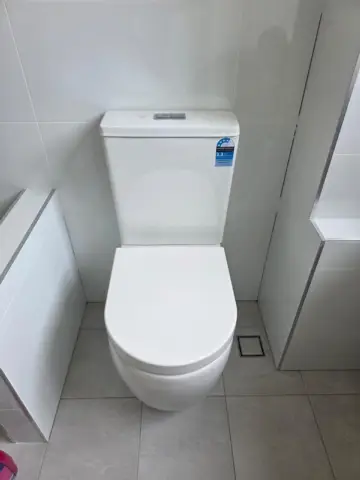 New close-coupled toilet installed in a tiled bathroom