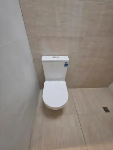 Toilet installation on beige floor tiles