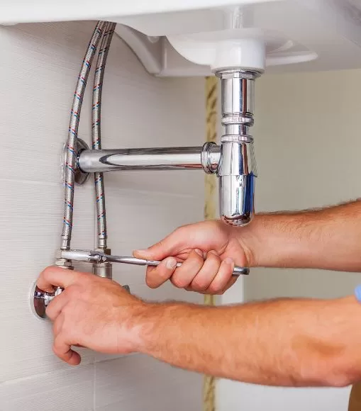 Hands turning off a water main valve as a DIY plumbing maintenance tip.